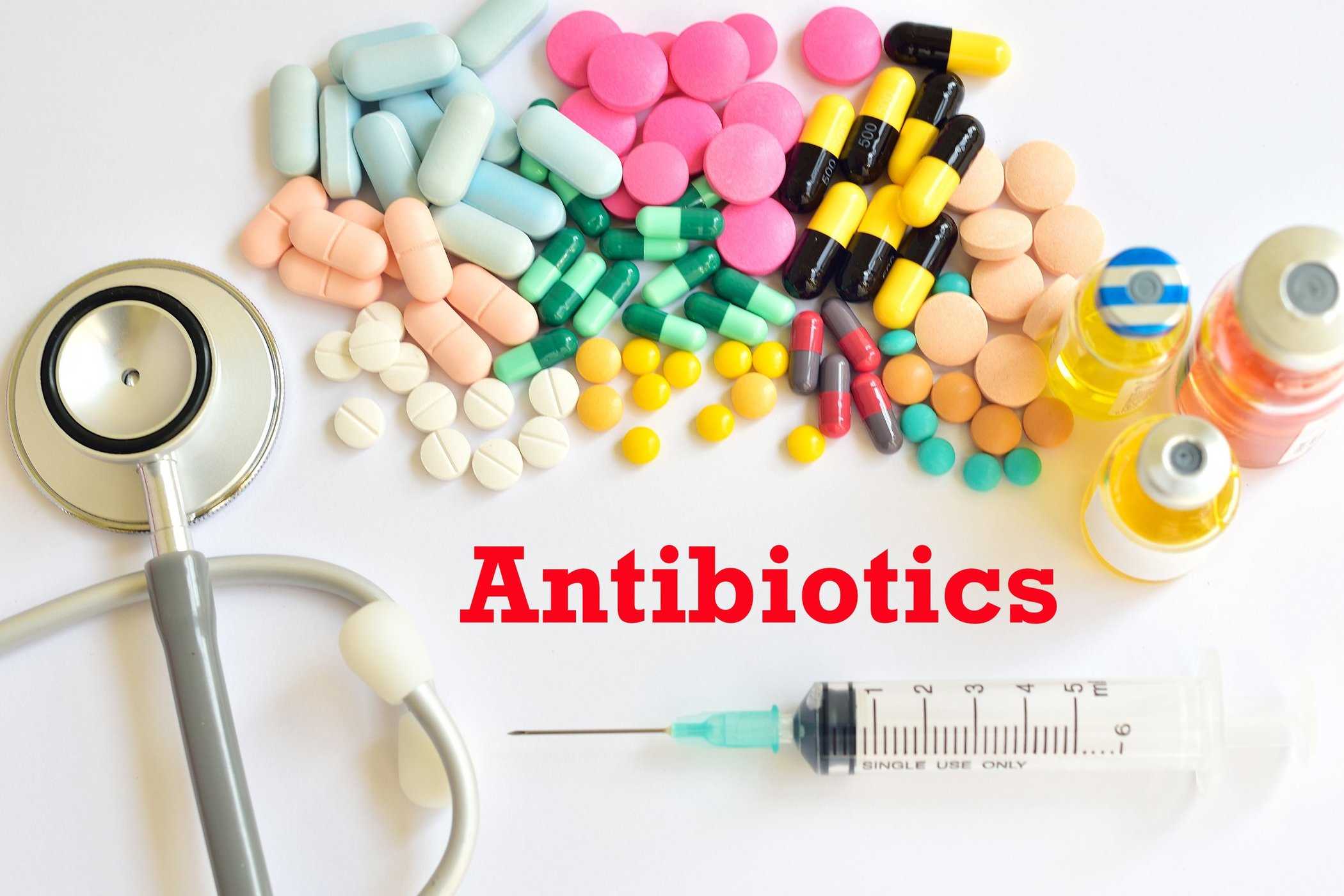 Таблетки и капсулы, стетоскоп, шприц и флаконы с надписью Antibiotics