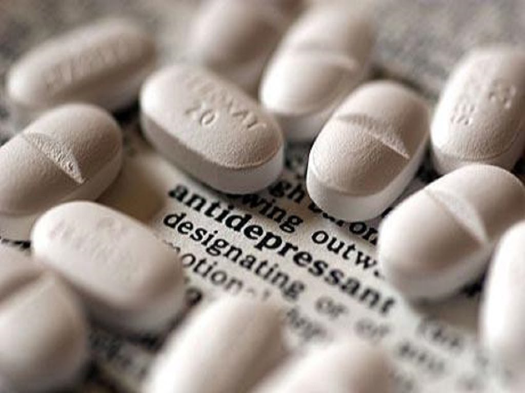 Горсть белых таблеток на газетной странице со словом antidepressant